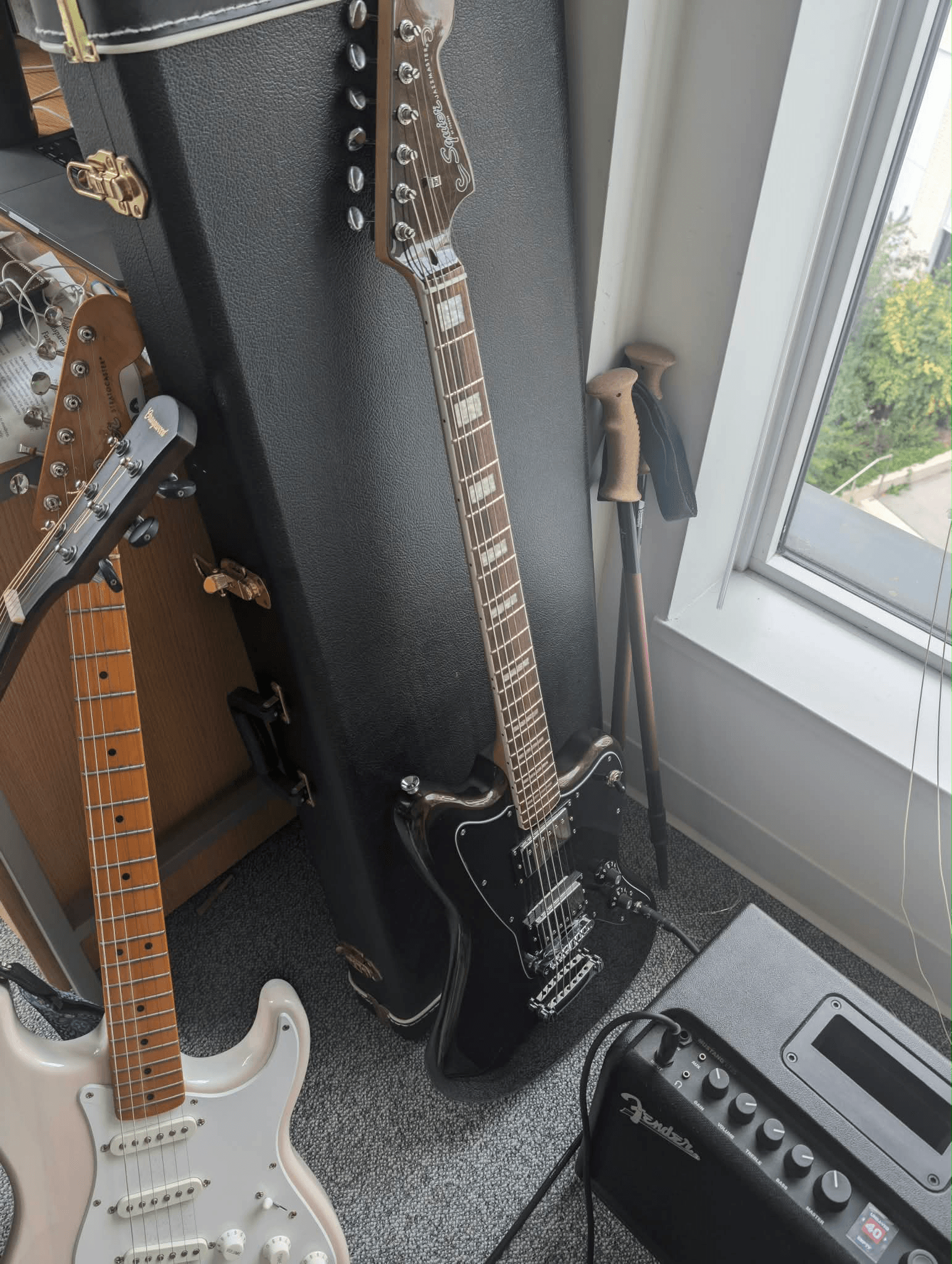My new baritone electric guitar beside my other guitars and a window.